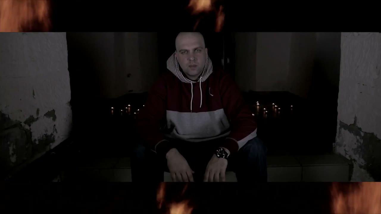 LAZAR sitzt zwischen Kerzen vor einer abgeblätterten Wand