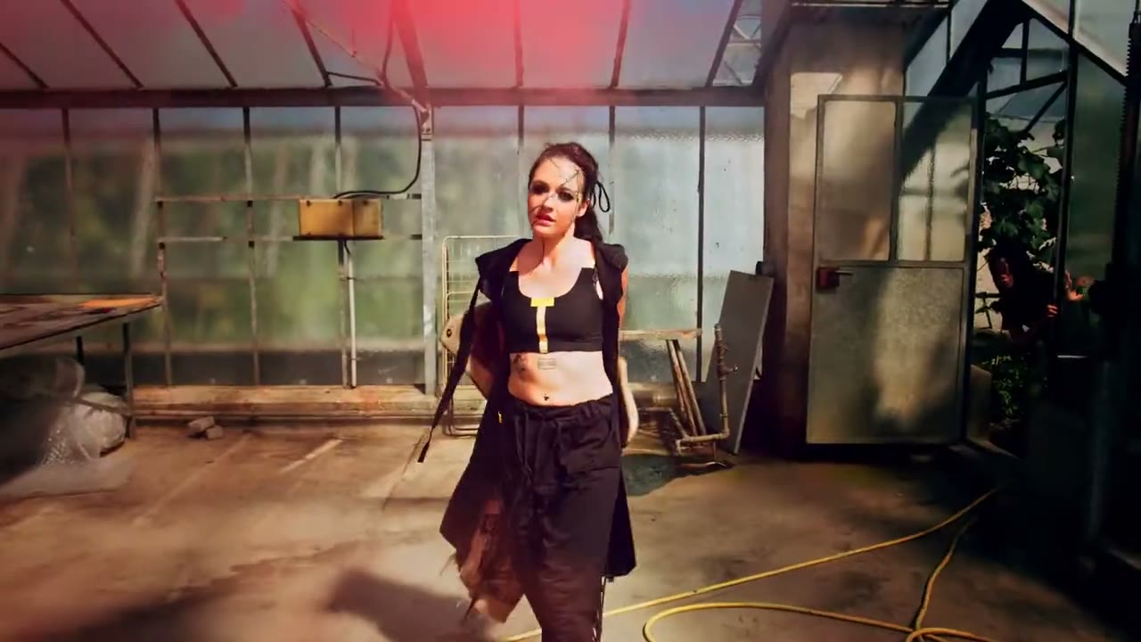 Model in Schwarz im Gewächshaus, rotes Licht von hinten