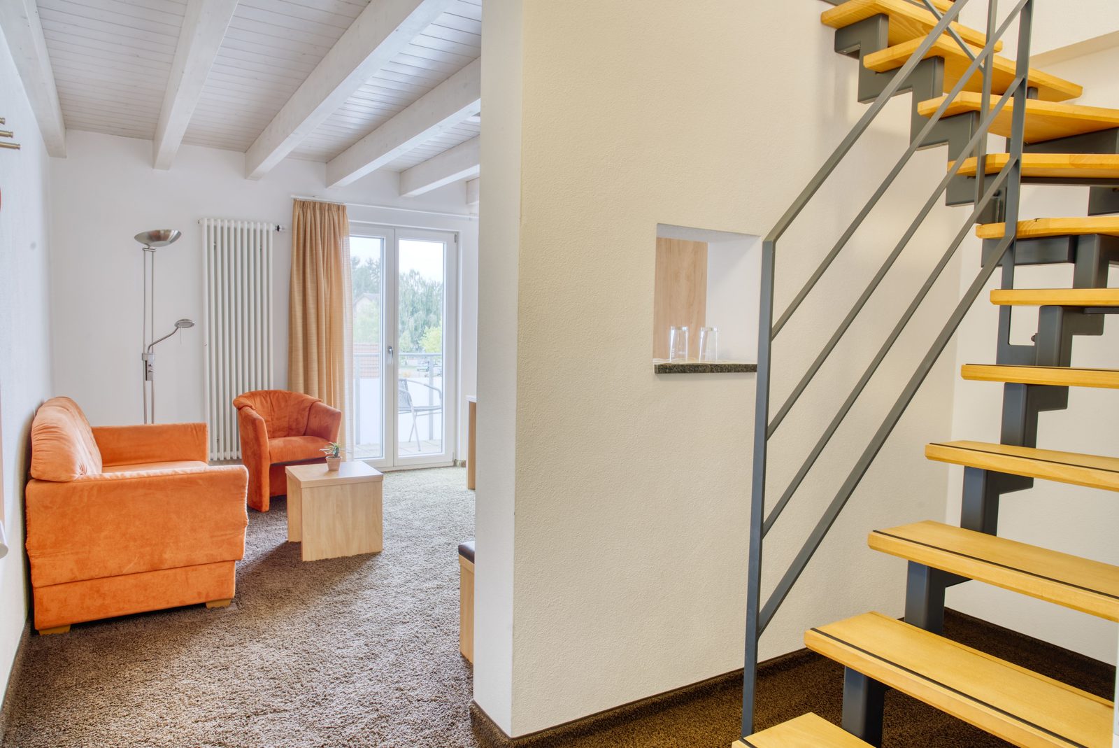 Wohnbereich der Suite mit offener Holztreppe ins Obergeschoss
