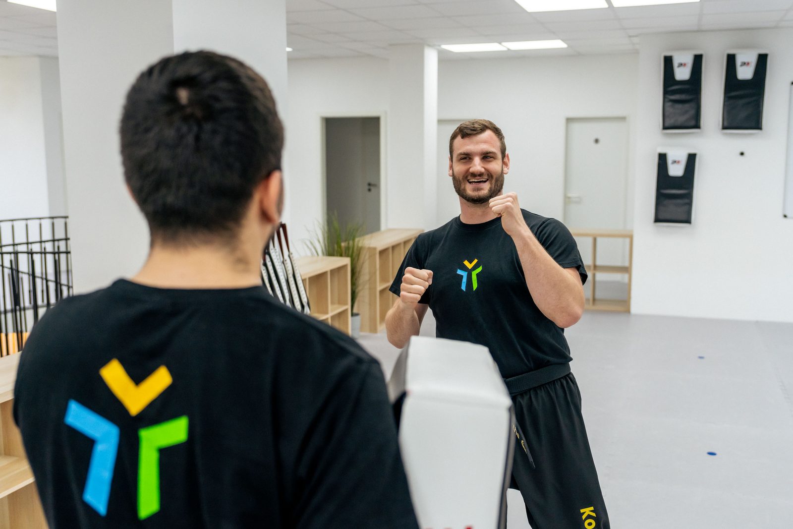 Trainer von hinten, das Zeichen gross auf dem schwarzen Shirt