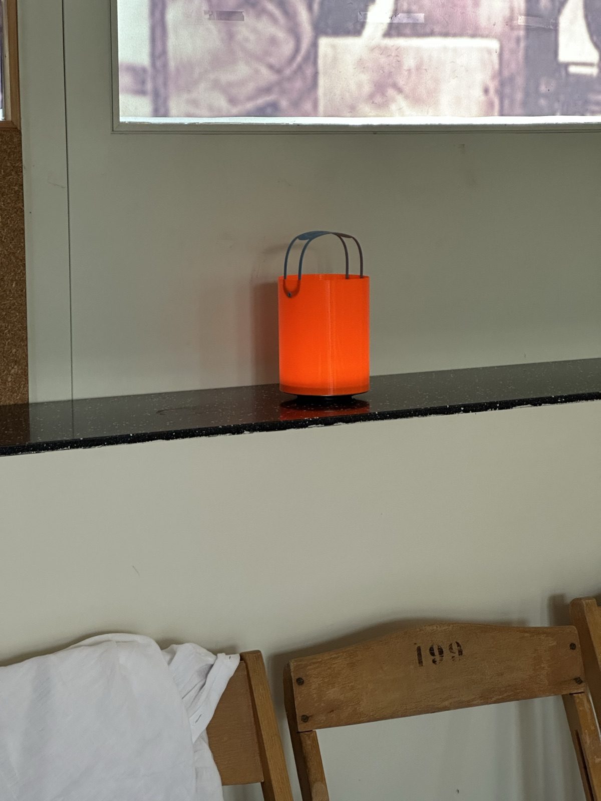 Kleine orange Leuchte mit Bügel auf einem Fenstersims