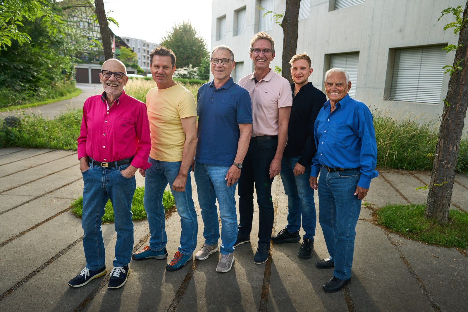 Gruppenbild: sechs Sänger nebeneinander auf dem Weg, lange Abendschatten